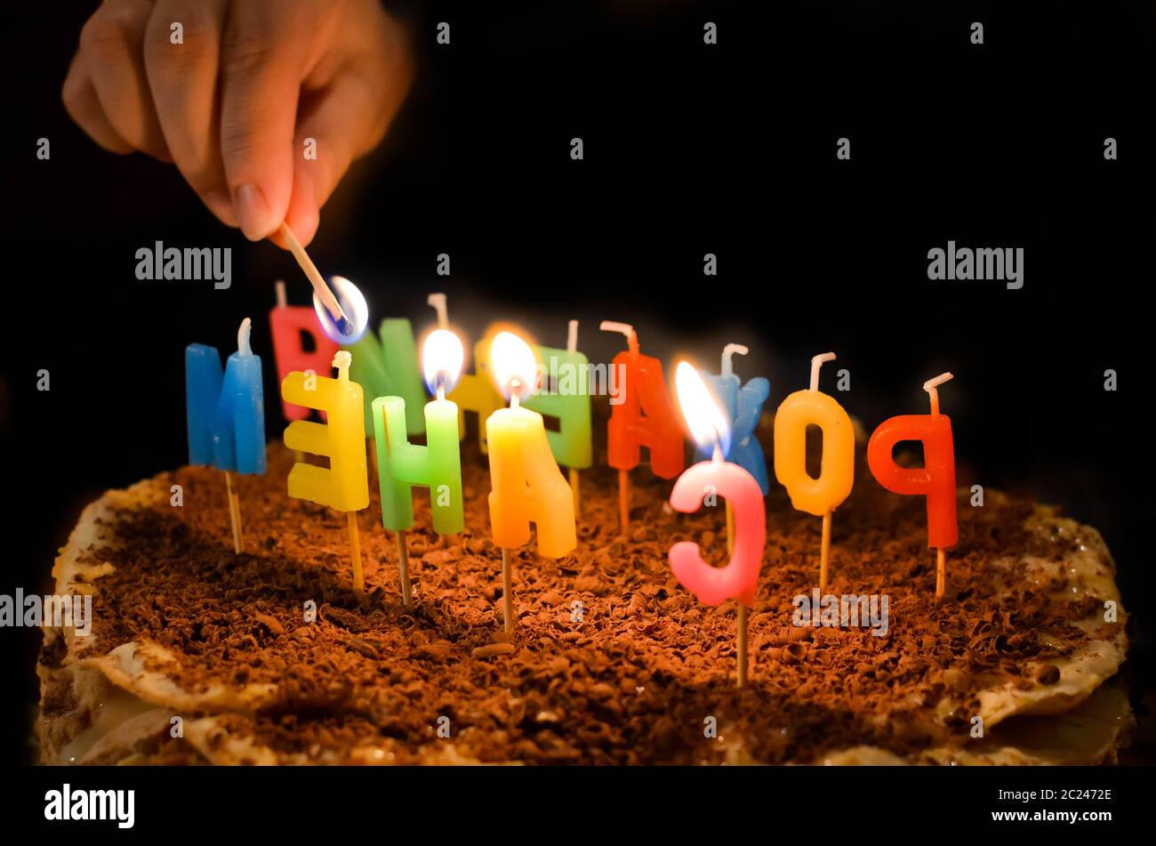 Torta di compleanno felice con candele di fuoco in forma di lettere russe Foto Stock