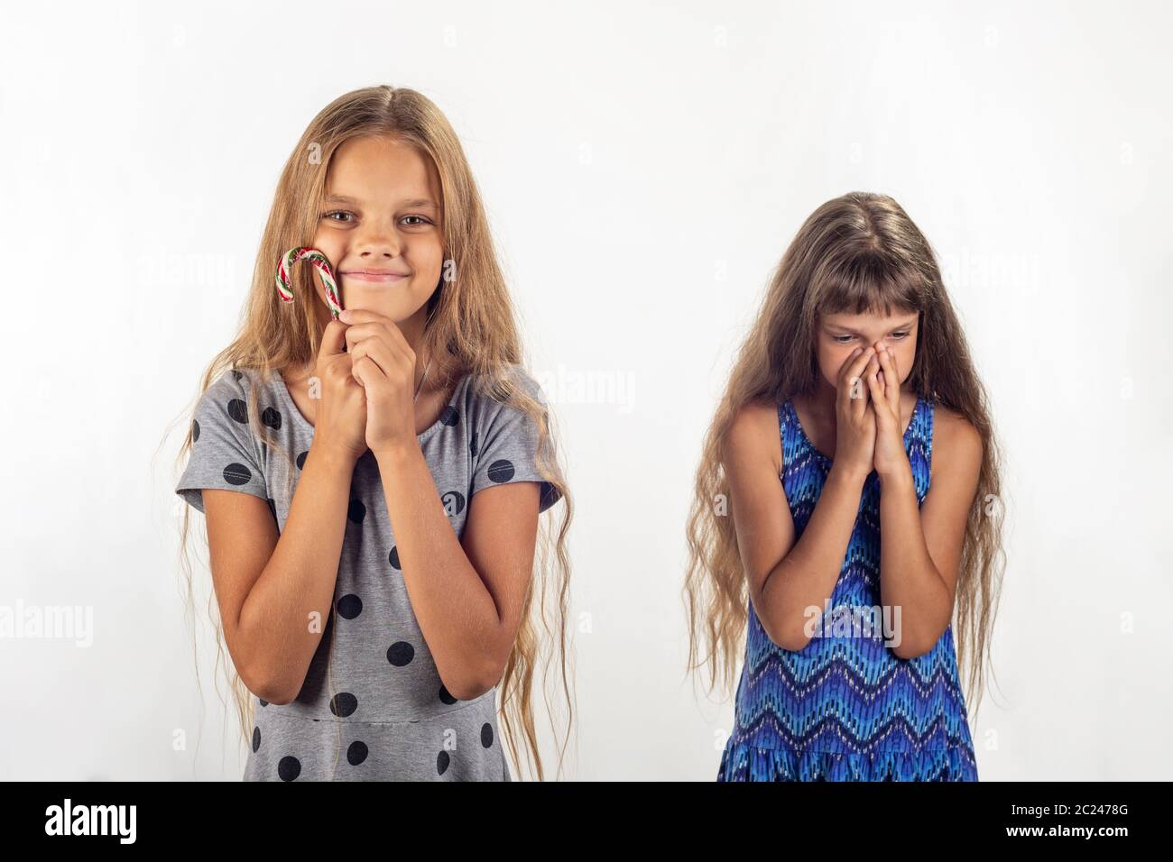 Una ragazza che è stato dato un lecca-lecca, l'altro non è stato Foto Stock