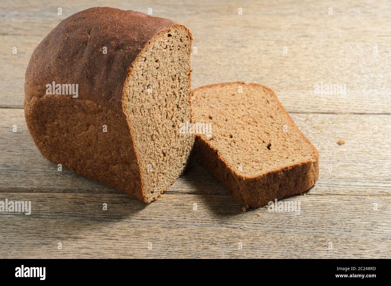 Pane nero fatto di farina di segale sullo sfondo di vecchi assi di cenere villaggio. Messa a fuoco selettiva. Foto Stock