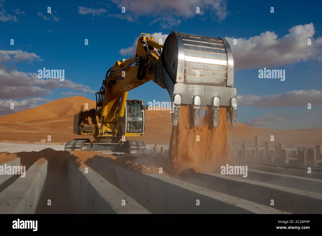 La sabbia di spostamento di pianta pesante sopra le forme di calcestruzzo, parte dei lavori per costruire un grande impianto petrolifero nel deserto del Sahara. Foto Stock