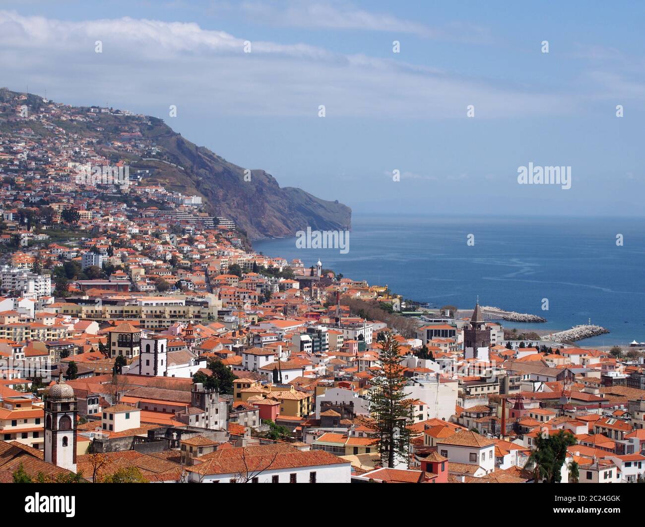 una vista soleggiata della città di funchal dall'alto con tetti ed edifici di fronte ad un mare blu luminoso Foto Stock