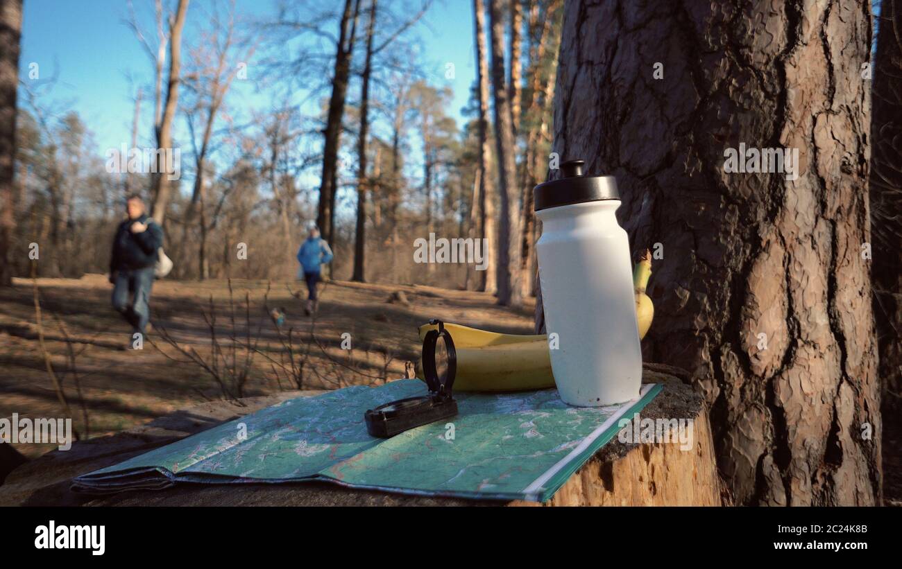 cose per il turismo viaggi per eco turismo nella foresta naturale. Carta, bussola e bottiglia di snack food con acqua e banana Foto Stock