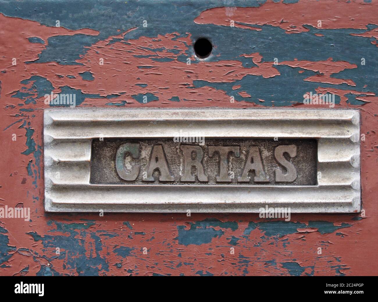una vecchia letterbox in metallo in una porta di legno rosso con spellatura vernice con la parola cartas, traduzione dal portoghese è posta Foto Stock