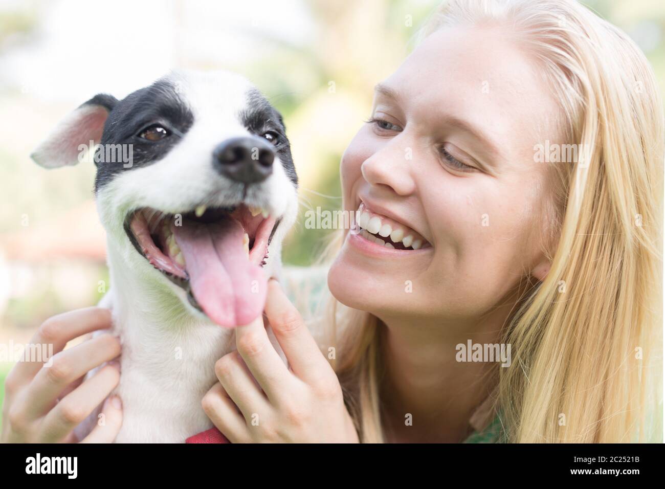 Un cane felice proprietario sorridente al suo cane carino al parco. Foto Stock