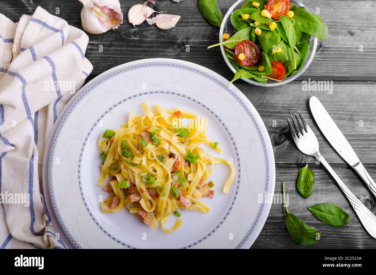 La pasta italiana con molla di cipolla, aglio e pancetta con insalata Foto Stock