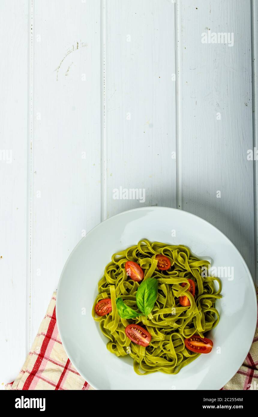 Gli spinaci tagliatelle al pesto di basilico e mini pomodori, wood board, tovaglioli e pesto mortaio Foto Stock