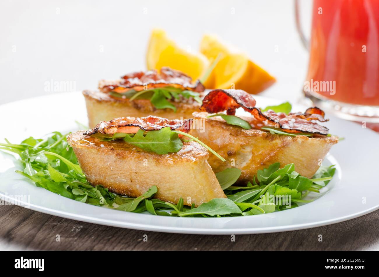 Toast alla francese con il miele e la pancetta, limonade dal rosso arancio e fresca insalata di rucola Foto Stock
