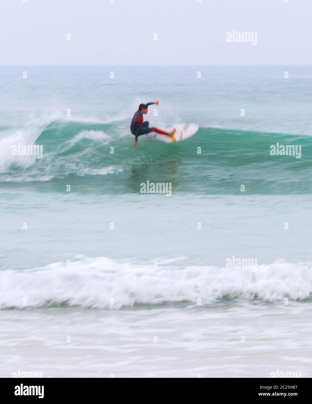 surfista che guida la sfocatura del movimento delle onde Foto Stock