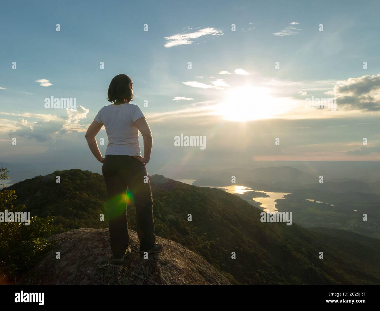 Persone non riconosciute - ragazza in cima montagna guardando paesaggio e diga serbatoio - tramonto retroilluminazione Foto Stock