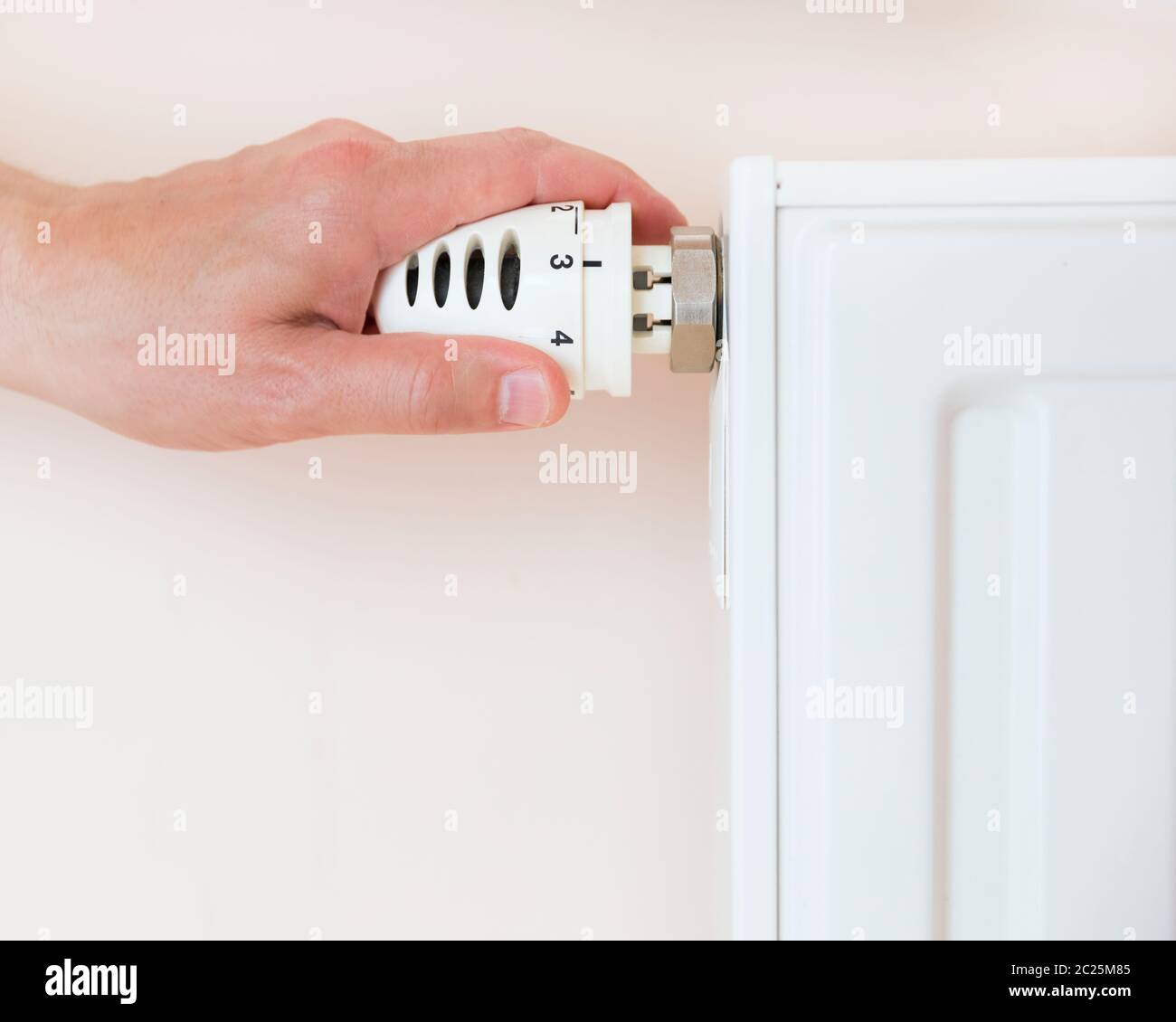 Regolazione manuale della valvola del termostato del radiatore di riscaldamento in un ambiente. Foto Stock