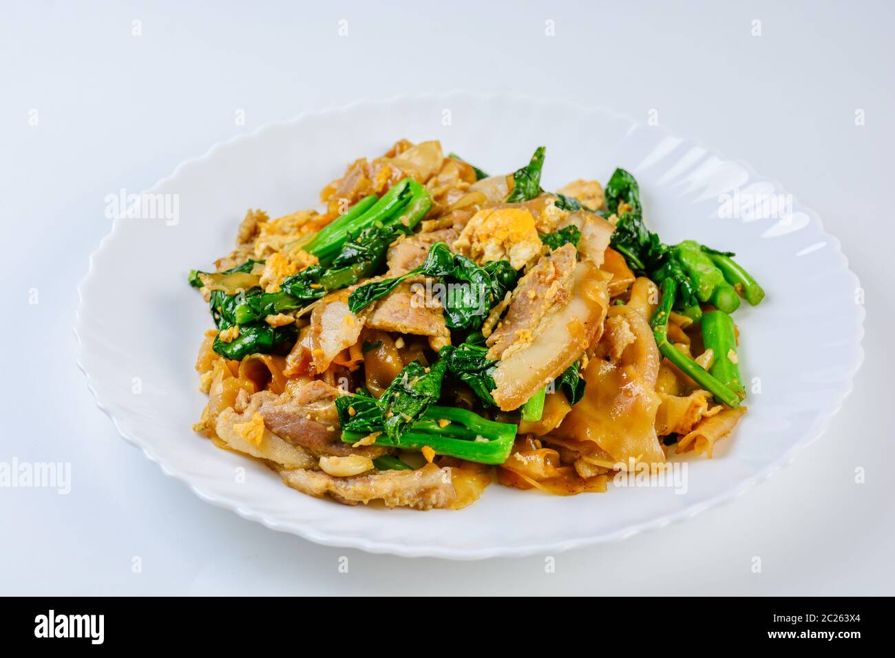 Saltati in padella il riso fresco-farina Tagliatelle con carne di maiale tagliata a fette, uovo e Kale. Quick noodle friggere. Foto Stock