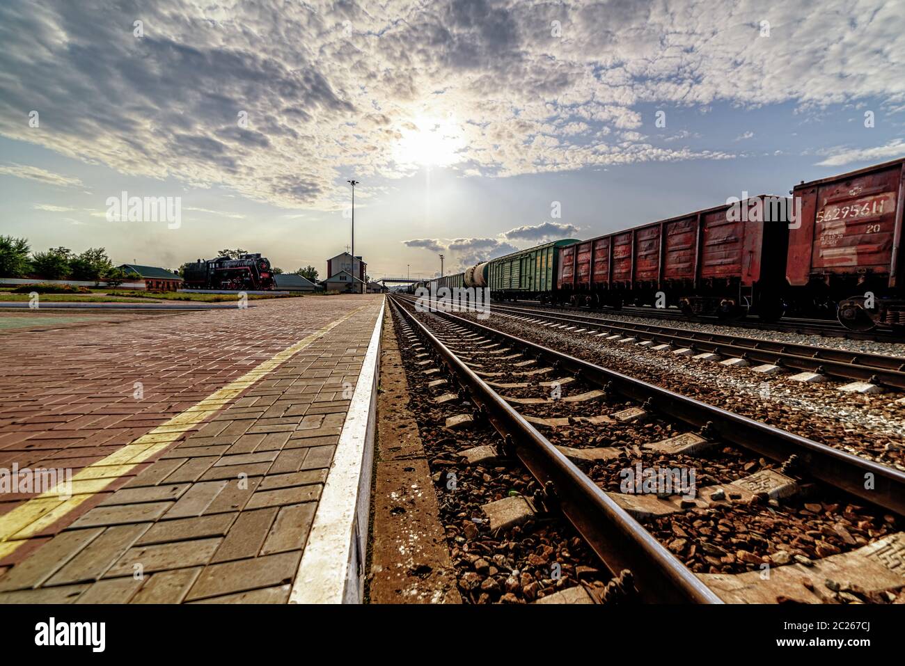 Vista dei binari ferroviari lungo la piattaforma, andando in lontananza. Cielo con nuvole Foto Stock