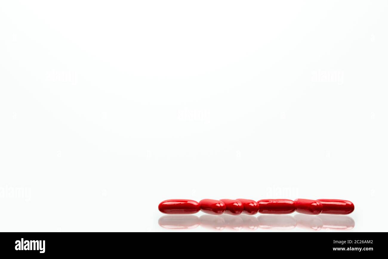 Capsula rossa pillole isolato su sfondo bianco con ombre e copia di spazio per il testo. La vitamina e supplemento per la gravidanza e le persone anziane. Foto Stock