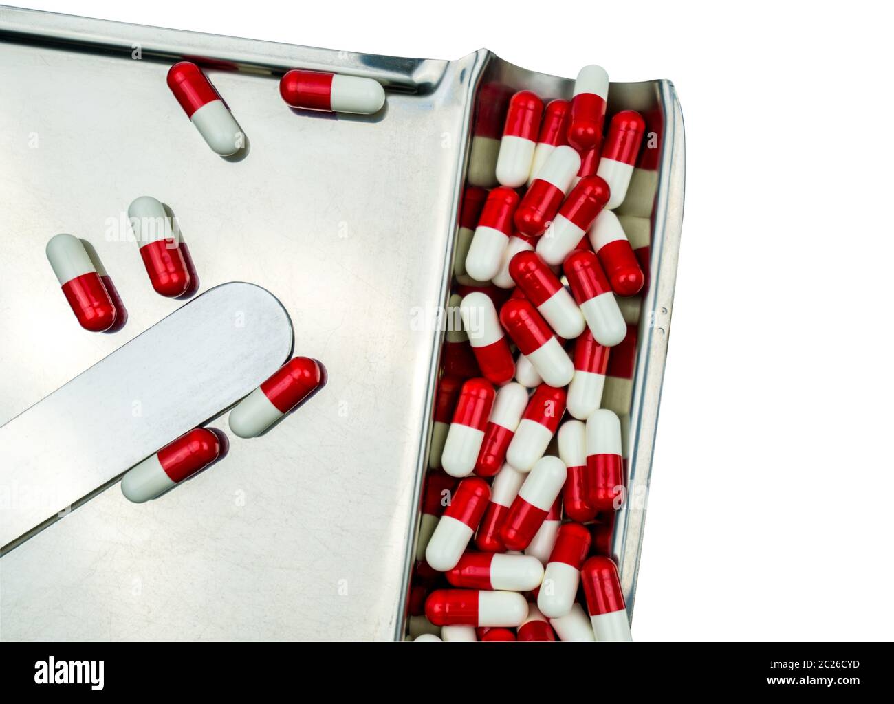 Vista dall'alto di capsule rosse di antibiotici bianchi isolate su vassoio portaricroga in acciaio inox con percorso di ritaglio, concetto di resistenza ai farmaci. Uso di droga con reas Foto Stock
