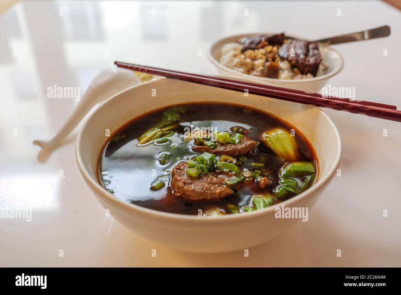 Zuppa di Noodle di manzo stufato taiwanese senza noodle in ciotola bianca su tavolo bianco e sfondo sfocato di Slow Cook Salsa di soia brasato di maiale Belly, con riso. Foto Stock
