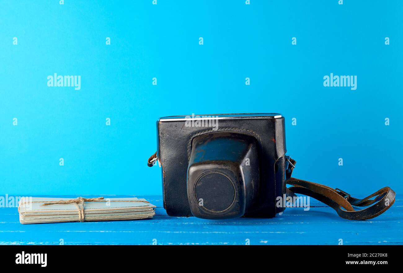 Vecchia fotocamera a pellicola in un marrone custodia in pelle su uno sfondo blu e corda legato cartoline vintage Foto Stock