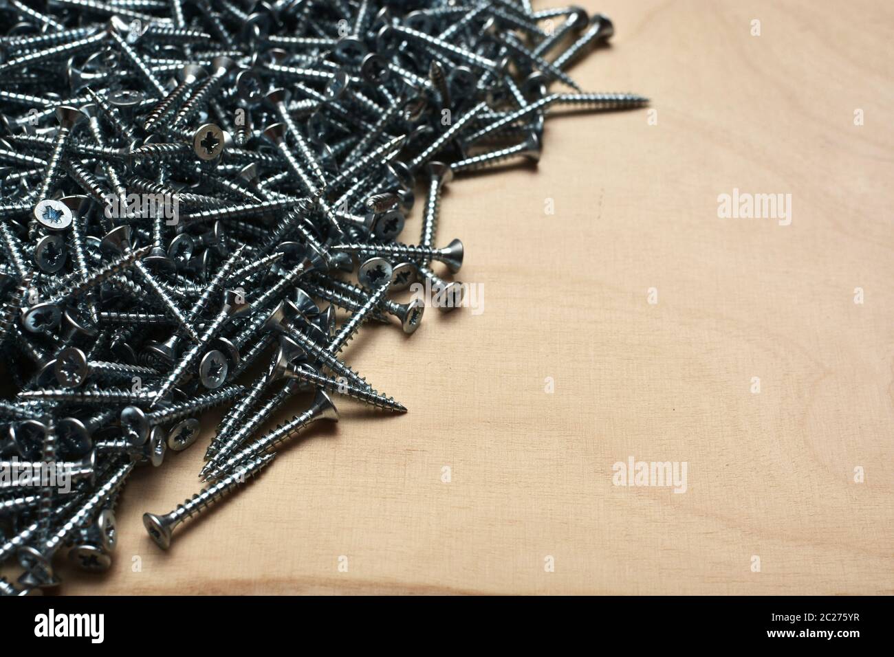 Viti metalliche su un foglio di legno compensato. Attrezzature per la produzione di mobili, attrezzature per la riparazione di hardware e appartamenti. Sfondo per impiallacciatura industriale. Foto Stock