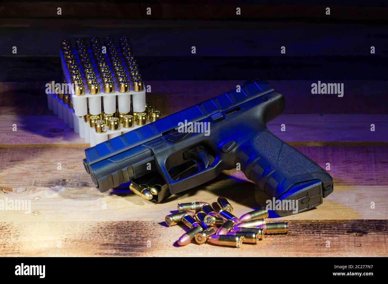 un moderno semi automatico arma poggiano una parte superiore di una rivista di munizioni di riserva con proiettili in eccesso in primo piano e una pila di munizioni nel backgroun Foto Stock