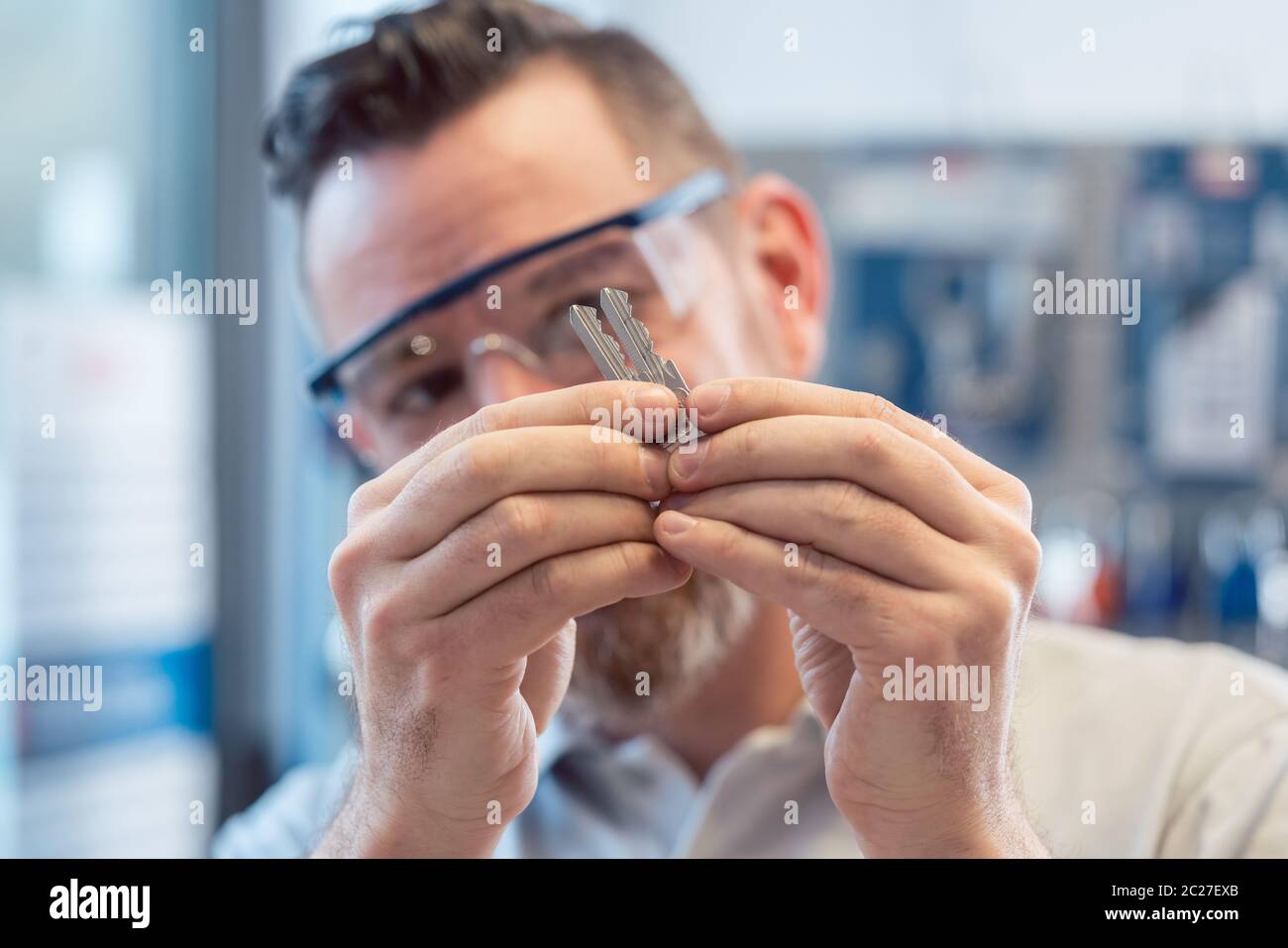 Uomo al negozio di taglierina per chiavi che guarda gli spazi vuoti che li confrontano Foto Stock