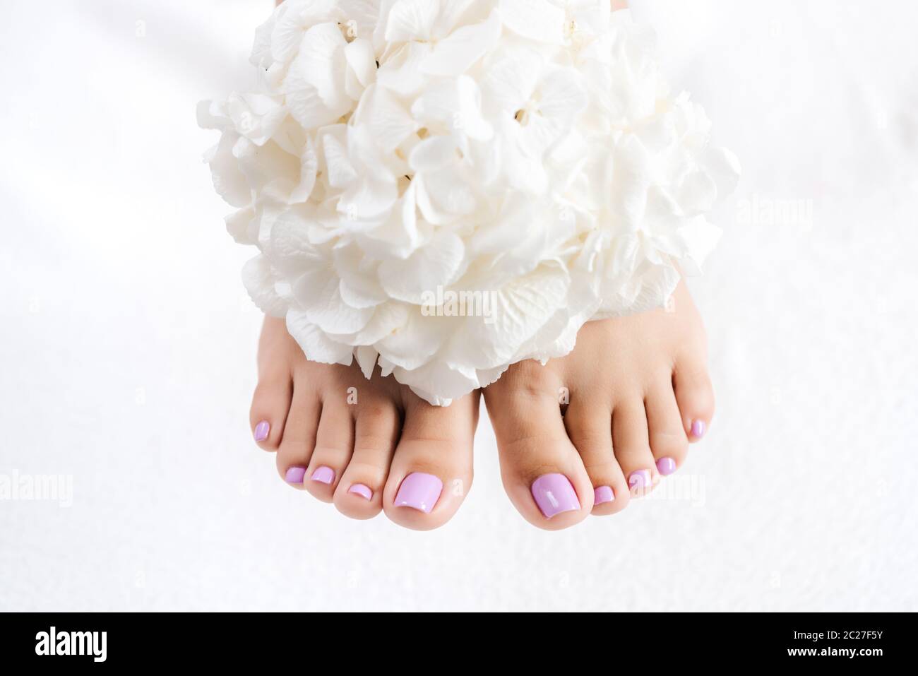 Piedi e chiocciole dopo pedicure con fiori bianchi Foto Stock
