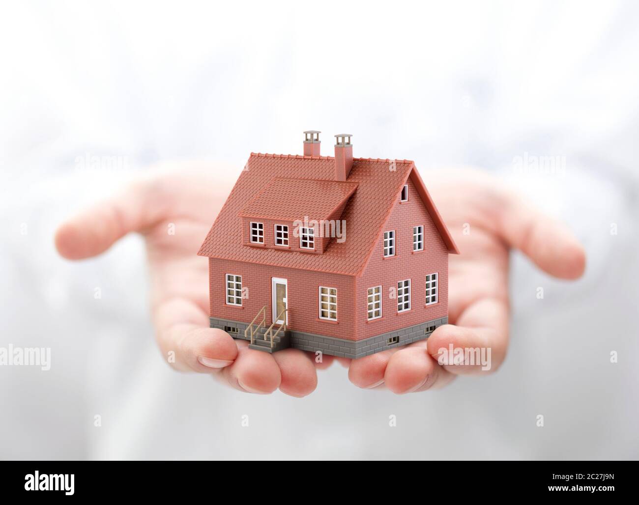 Casa marrone miniatura in mani Foto Stock