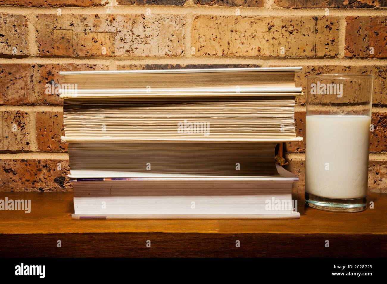 Bicchiere di latte e libri su un mantello camino Foto Stock
