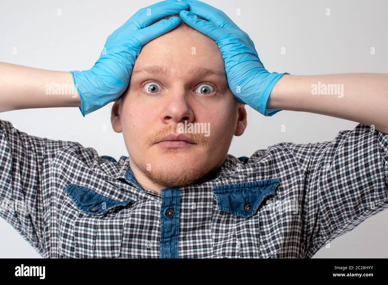 un giovane uomo in guanti blu madicina ha un panico emozioni tenere sulla testa. coronavirus concetto. pandemia Foto Stock