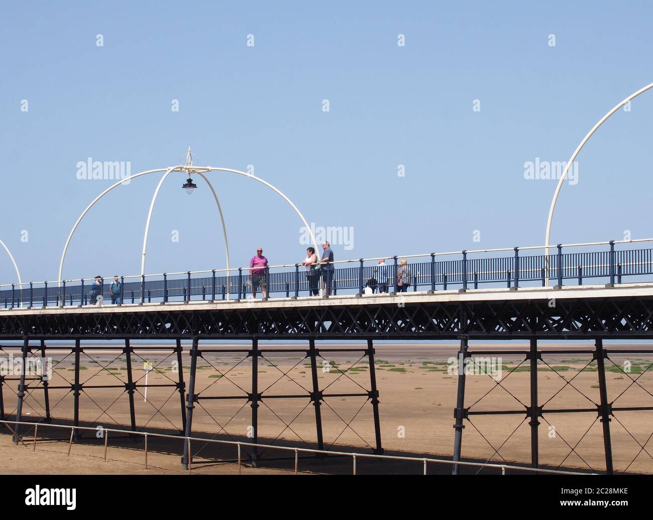 persone sul molo storico a southport merseyside con la spiaggia esposta a bassa marea in una giornata estiva luminosa Foto Stock