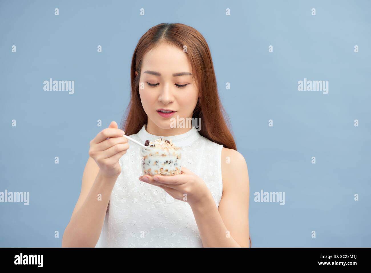 Ritratto di bella ragazza sorridente in forma con yogurt, uvetta e farinata d'avena. Foto Stock