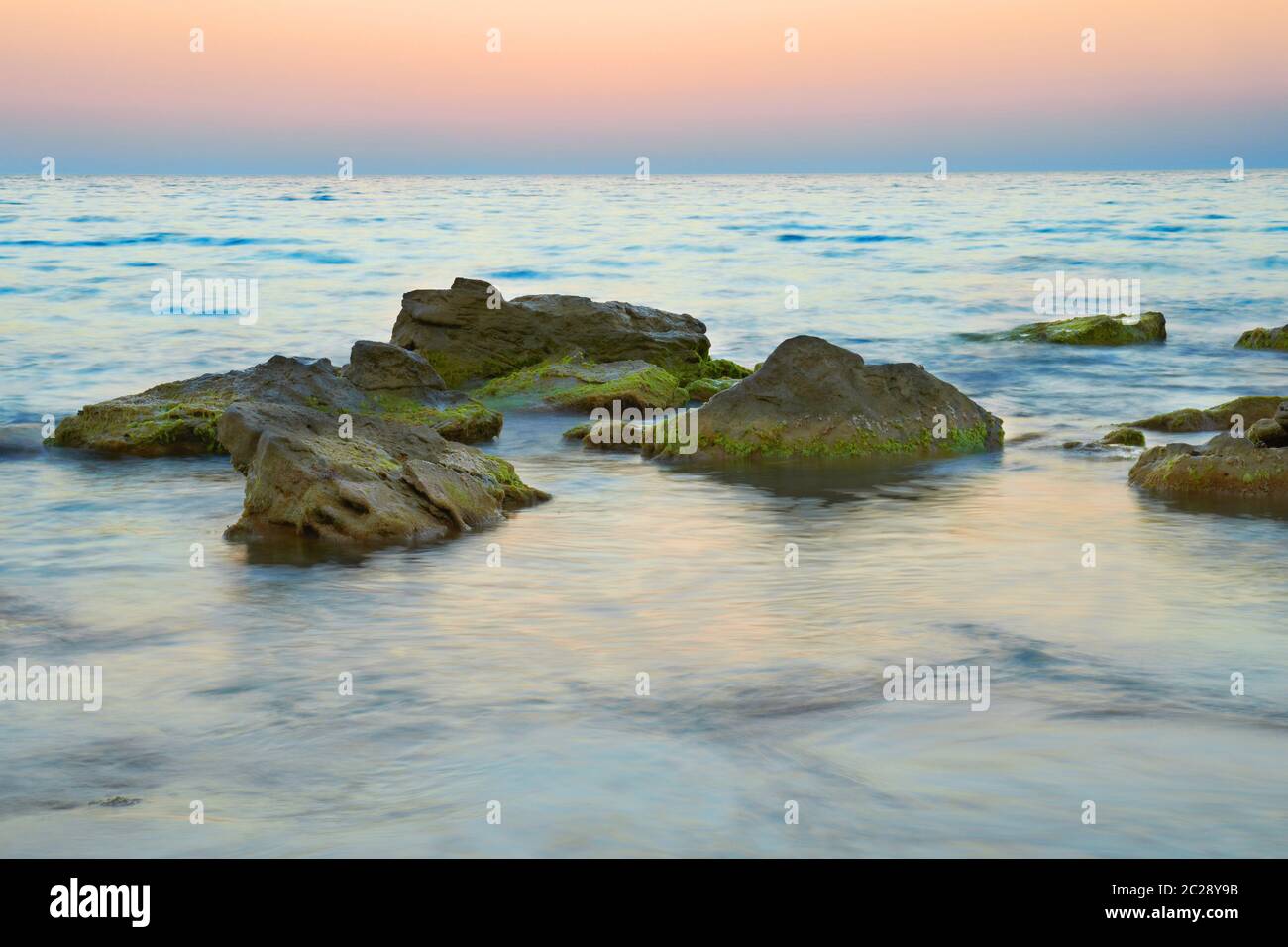 Le rocce in mare contro il bellissimo tramonto Foto Stock