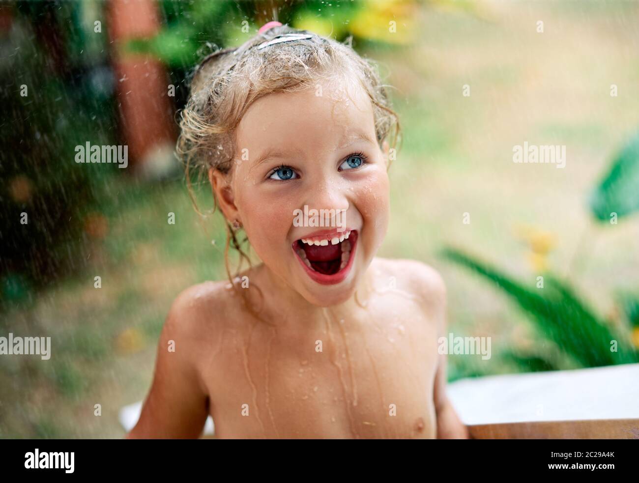 Primo piano ritratto di felice carina bambina godere di pioggia estiva Foto Stock