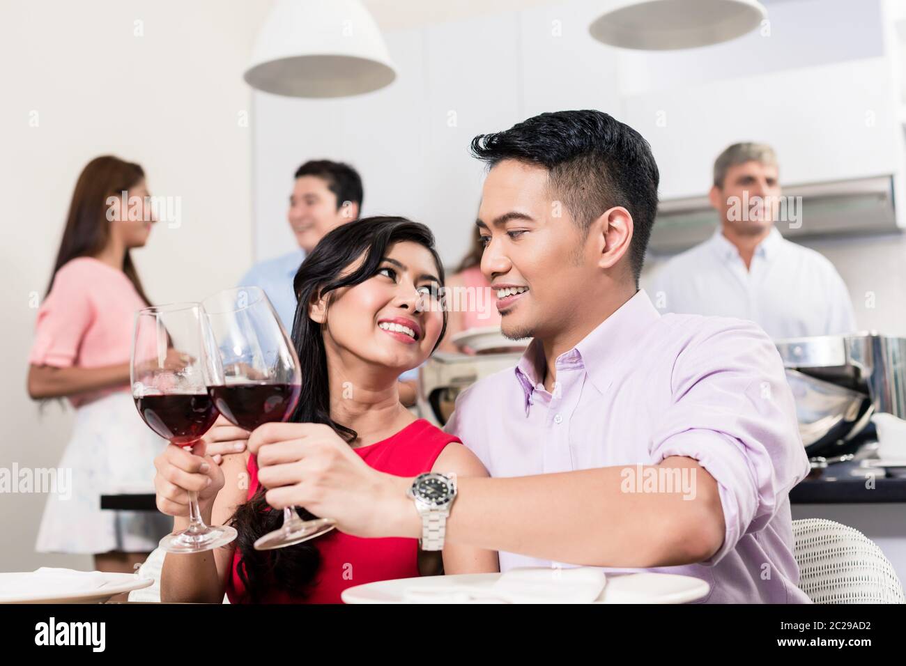 Ritratto di giovane coppia sorridente che brinda bicchieri di vino rosso nella festa Foto Stock