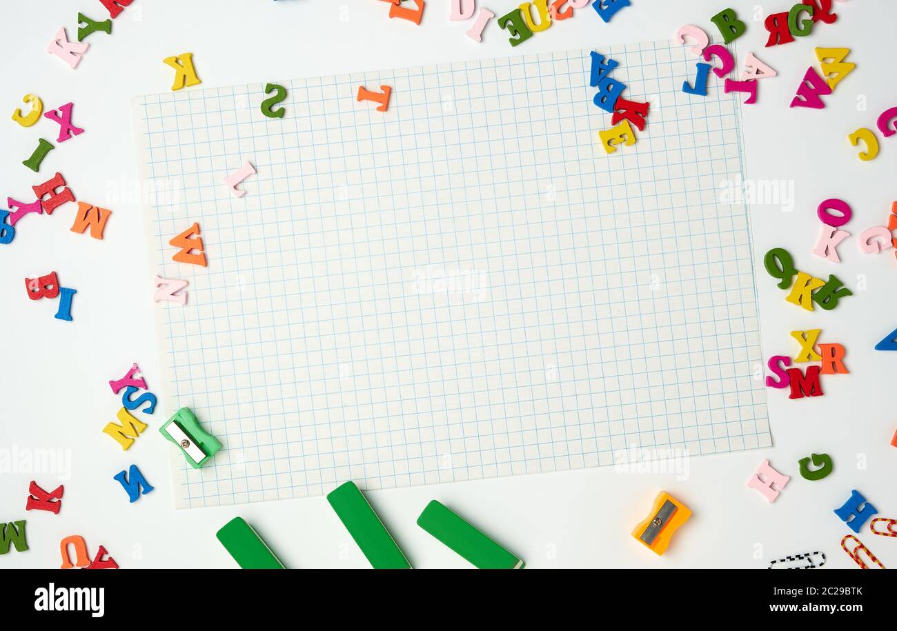 Fogli bianchi in una gabbia e piccole multi-colore lettere in legno, torna a scuola, spazio di copia Foto Stock