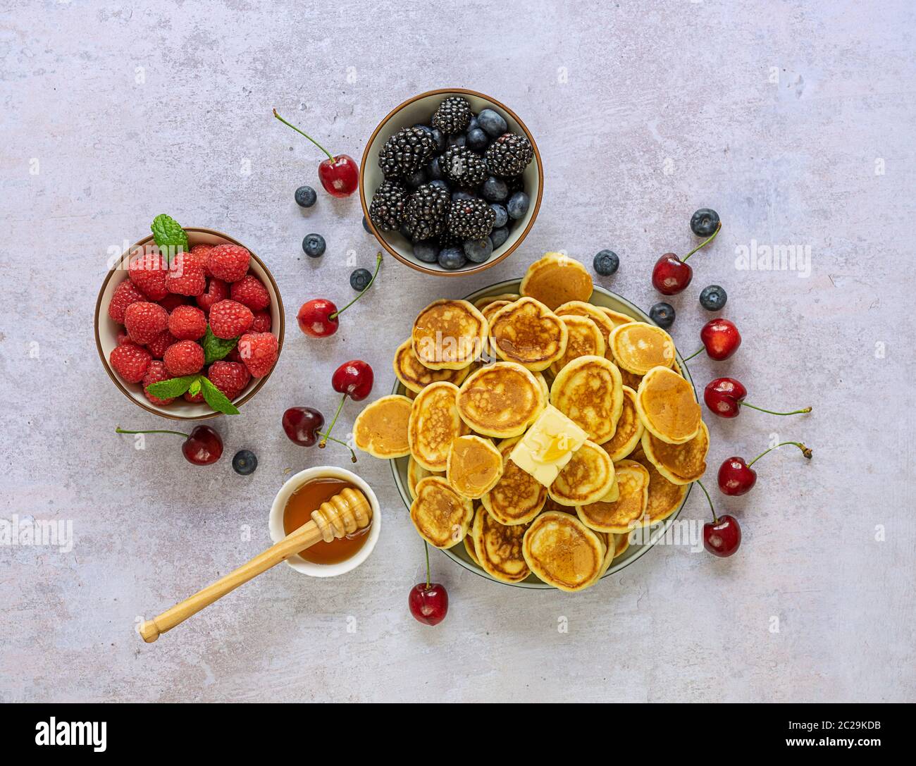 Ciotola con minuscola frittella di cereali con frutti di bosco e sciroppo d'acero. Foto Stock