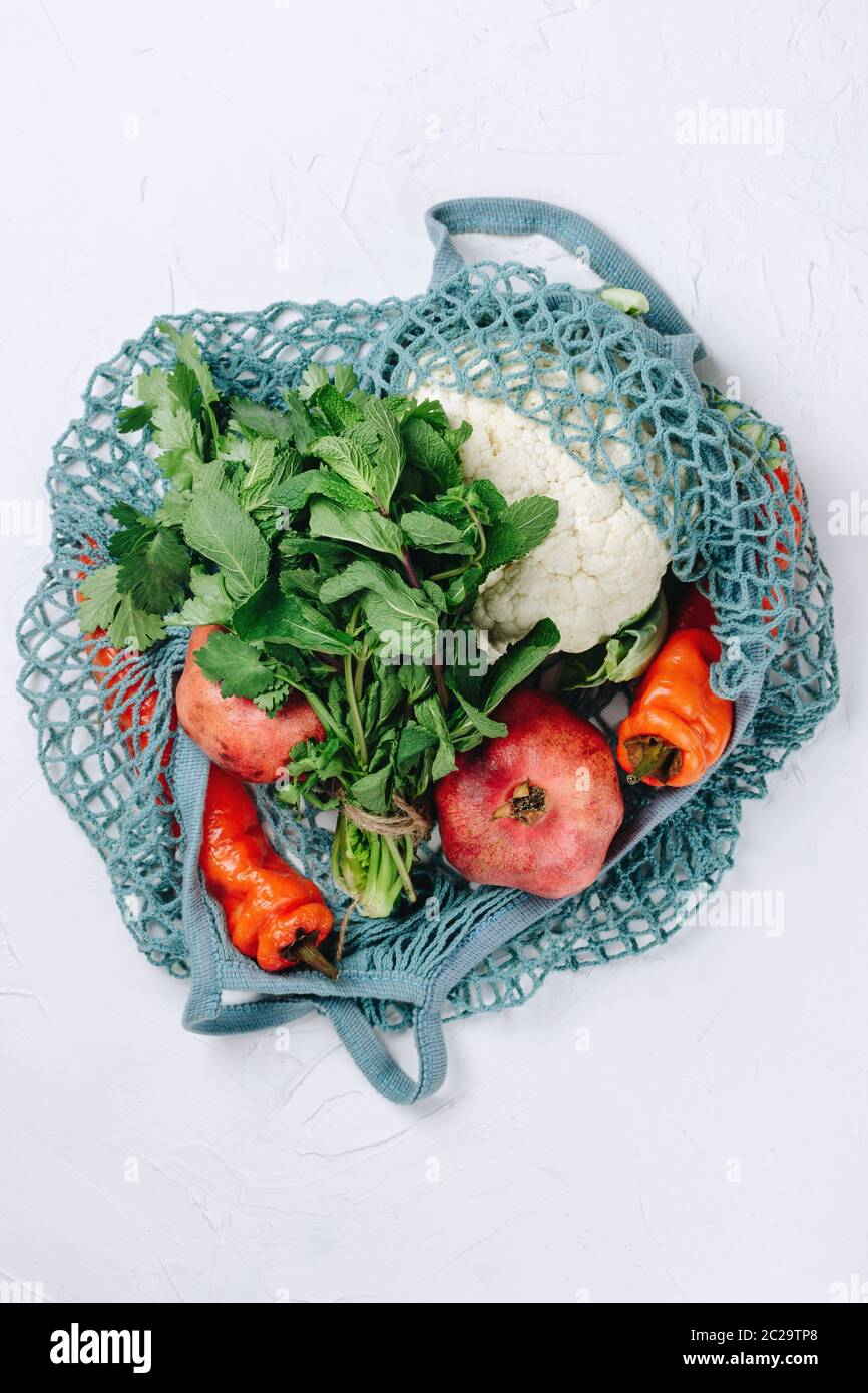 Flatlay di zero rifiuti di cibo sostenibile shopping, frutta varie, verdure e verdi in una borsa di maglia blu Foto Stock