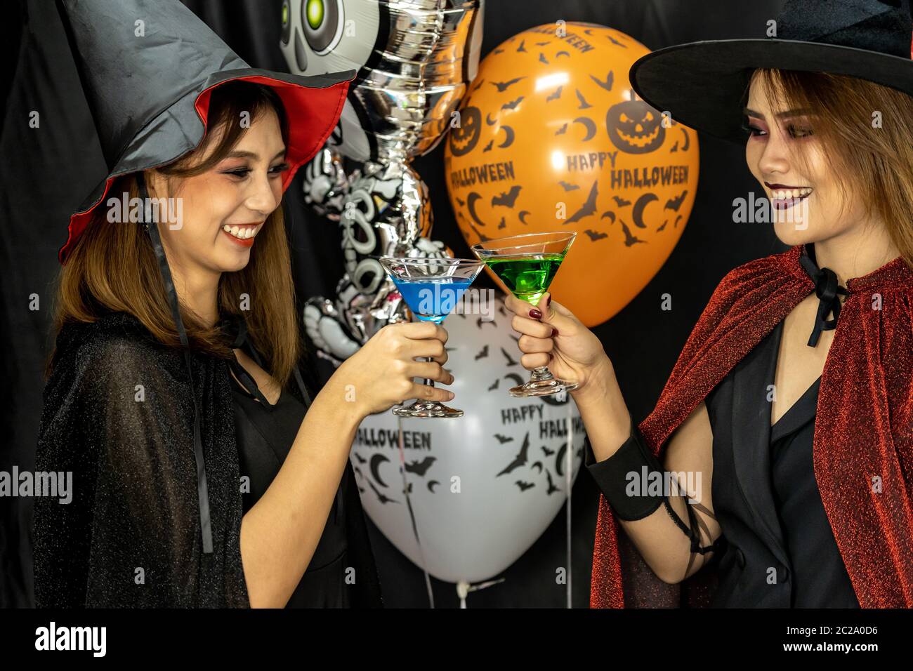 Un gruppo di giovani e di adulti di adolescente persone celebrare una festa di Halloween festa di carnevale in costume di Halloween di bere alcol cocktail Foto Stock