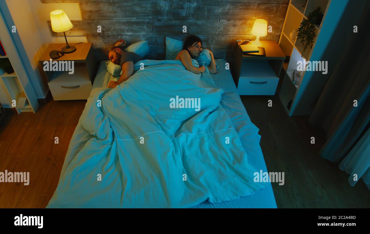La giovane coppia sotto le lenzuola non può dormire dopo un disaccordo. Luce blu luna. Foto Stock