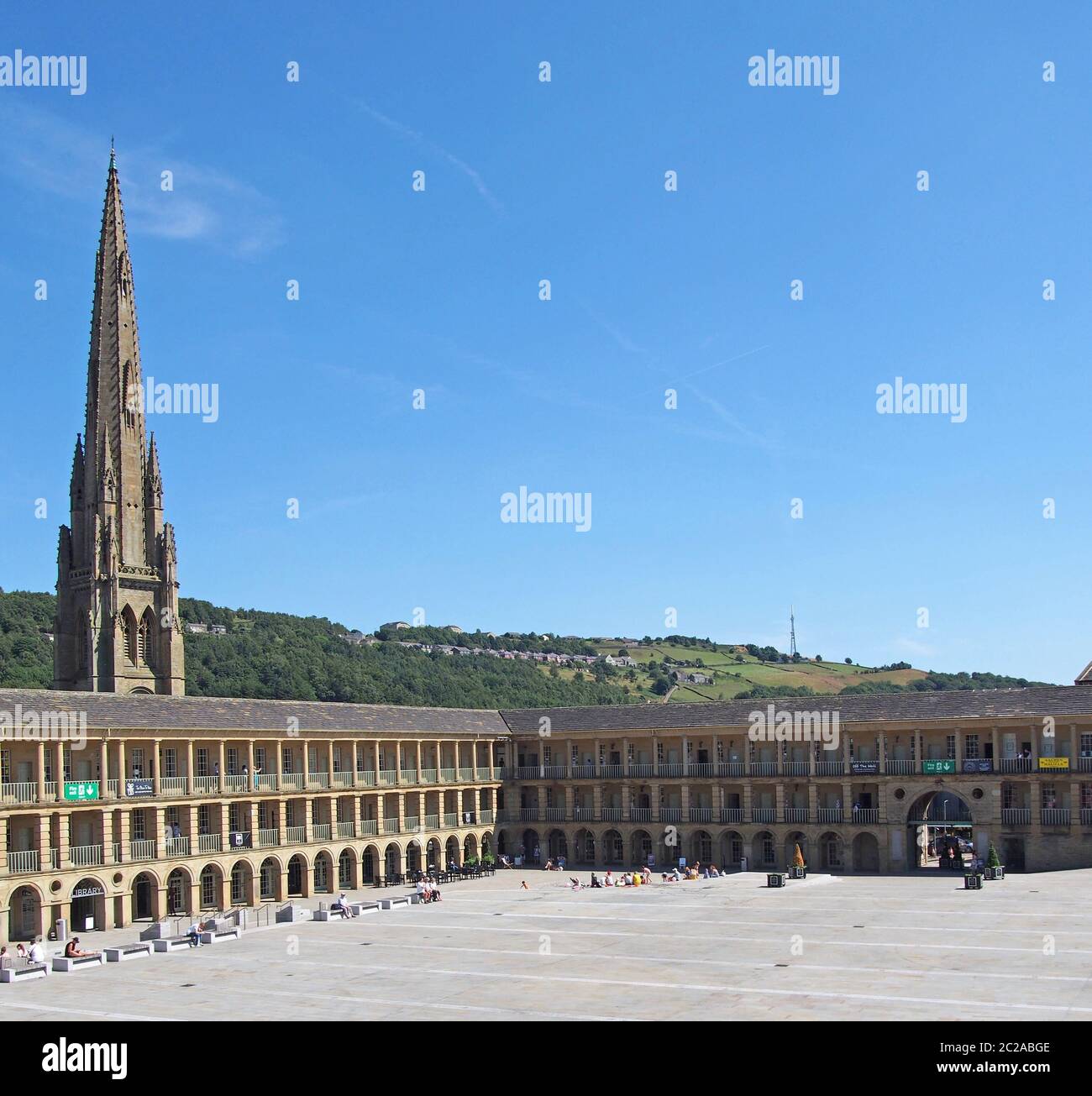 le persone si rilassano e godendo il sole estivo nella piazza di halifax pezzo sala nella parte occidentale dello yorkshire con colline circostanti an Foto Stock