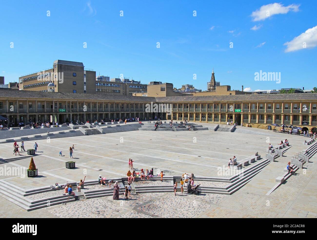 le persone si rilassano sui gradini e nei caffè godendo del sole estivo nella piazza della sala pezzi halifax nella parte occidentale dello yorkshire Foto Stock