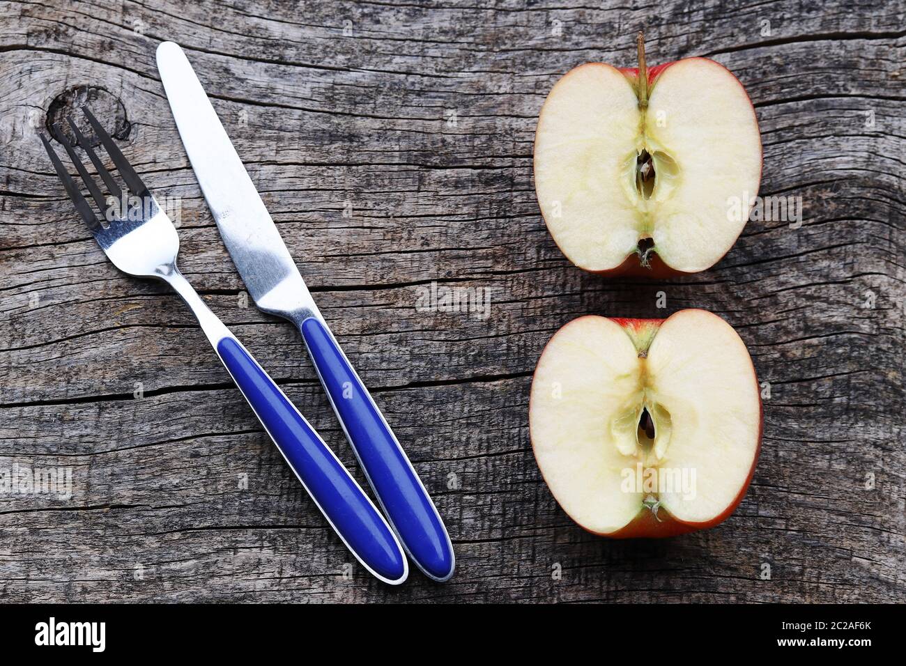 Due mezze mele e coltello e forchetta su un vecchio tavolo di legno Foto Stock