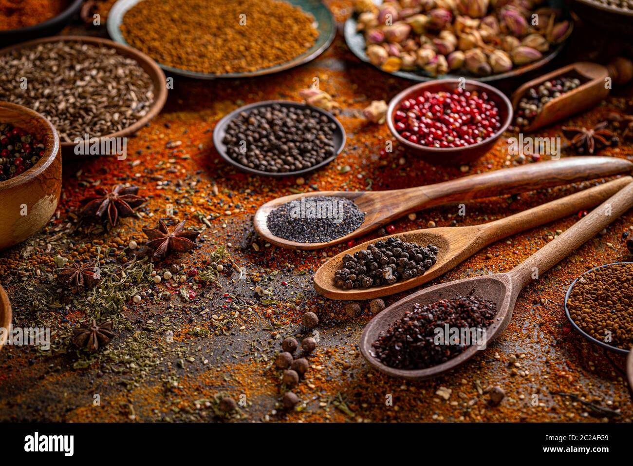 Spezie colorate in cucchiai di legno. Bellissima cucina immagine. Foto Stock