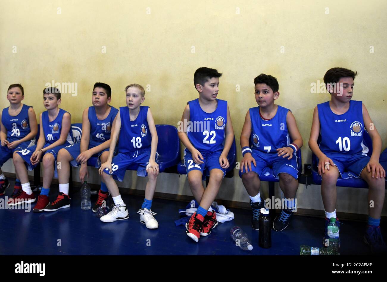 La squadra di basket per bambini si siede in panchina, durante il time-out, di una gara finale di basket per bambini, a Milano. Foto Stock