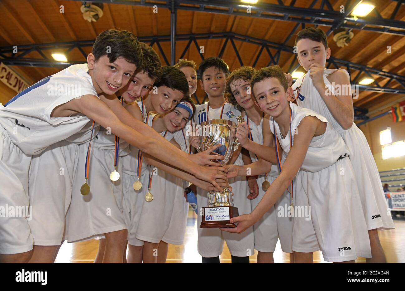 La squadra di pallacanestro dei bambini tiene la coppa del trofeo, per celebrare la vittoria di una gara finale di basket per bambini, a Milano. Foto Stock