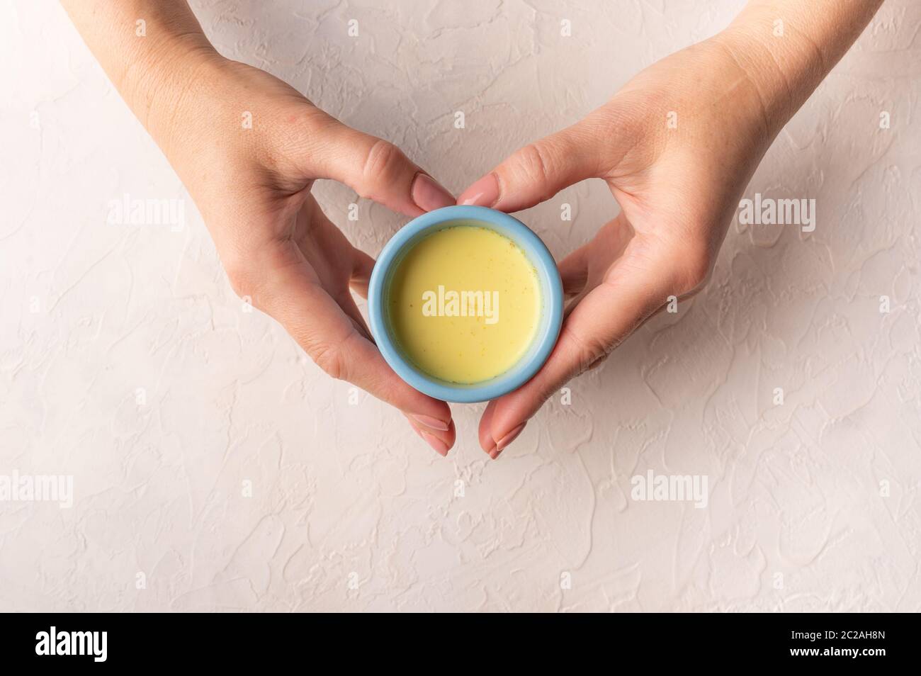 Le mani delle donne nella forma di una tazza blu di ceramica di tenuta del cuore con il tè indiano tradizionale masala chai. Vista dall'alto con spazio per la copia Foto Stock