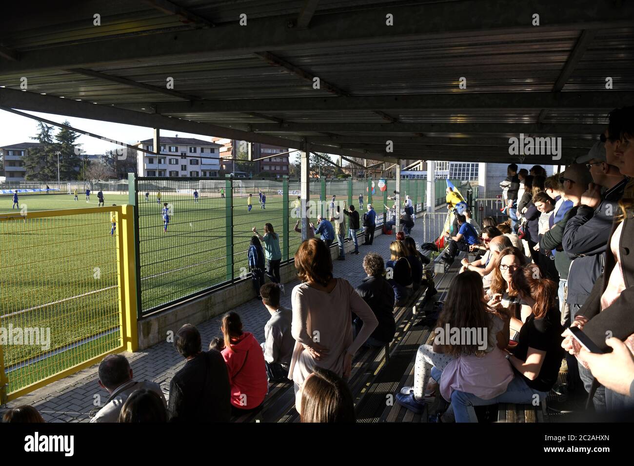 Genitori che seguono e sostengono una partita di calcio per bambini in tribuna, a Milano. Foto Stock