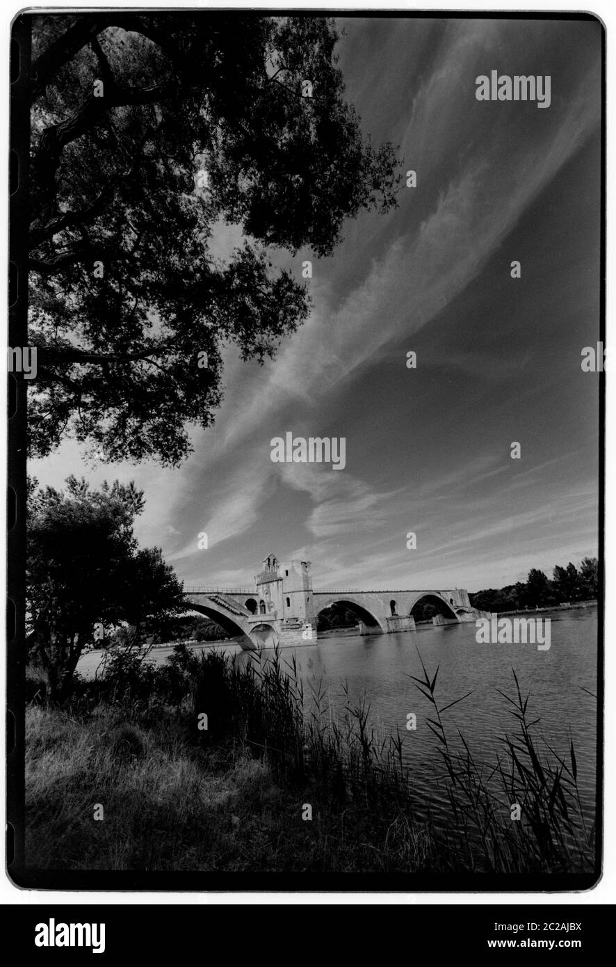 Ponte di Avignone. Il Pont Saint-Bénézet, Pont d'Avignon, 1988 Wikipedia: Il Pont Saint-Bénézet , noto anche come Pont d'Avignon, è un famoso ponte medievale nella città di Avignone, nel sud della Francia. Un ponte di legno che attraversa la Rhône tra Villeneuve-lès-Avignone e Avignone è stato costruito tra il 1177 e il 1185. Questo primo ponte fu distrutto quarant'anni più tardi nel 1226 durante la Crociata Albigese quando Luigi VIII di Francia assediò Avignone. A partire dal 1234 il ponte fu ricostruito con 22 archi in pietra. Il ponte di pietra era lungo circa 900 m (980 yd) e largo solo 4.9 m (16 ft) Foto Stock