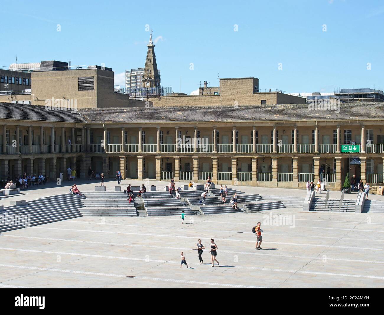 le persone si rilassano sui gradini e nei caffè godendo del sole estivo nella piazza della sala pezzi halifax nella parte occidentale dello yorkshire Foto Stock