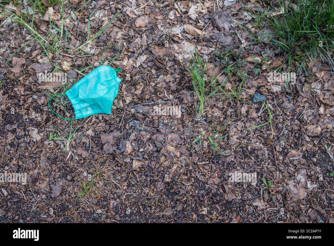 Maschera protettiva per la protezione contro il coronavirus gettato nella foresta. Il concetto di littering l'ambiente durante una pandemia Foto Stock