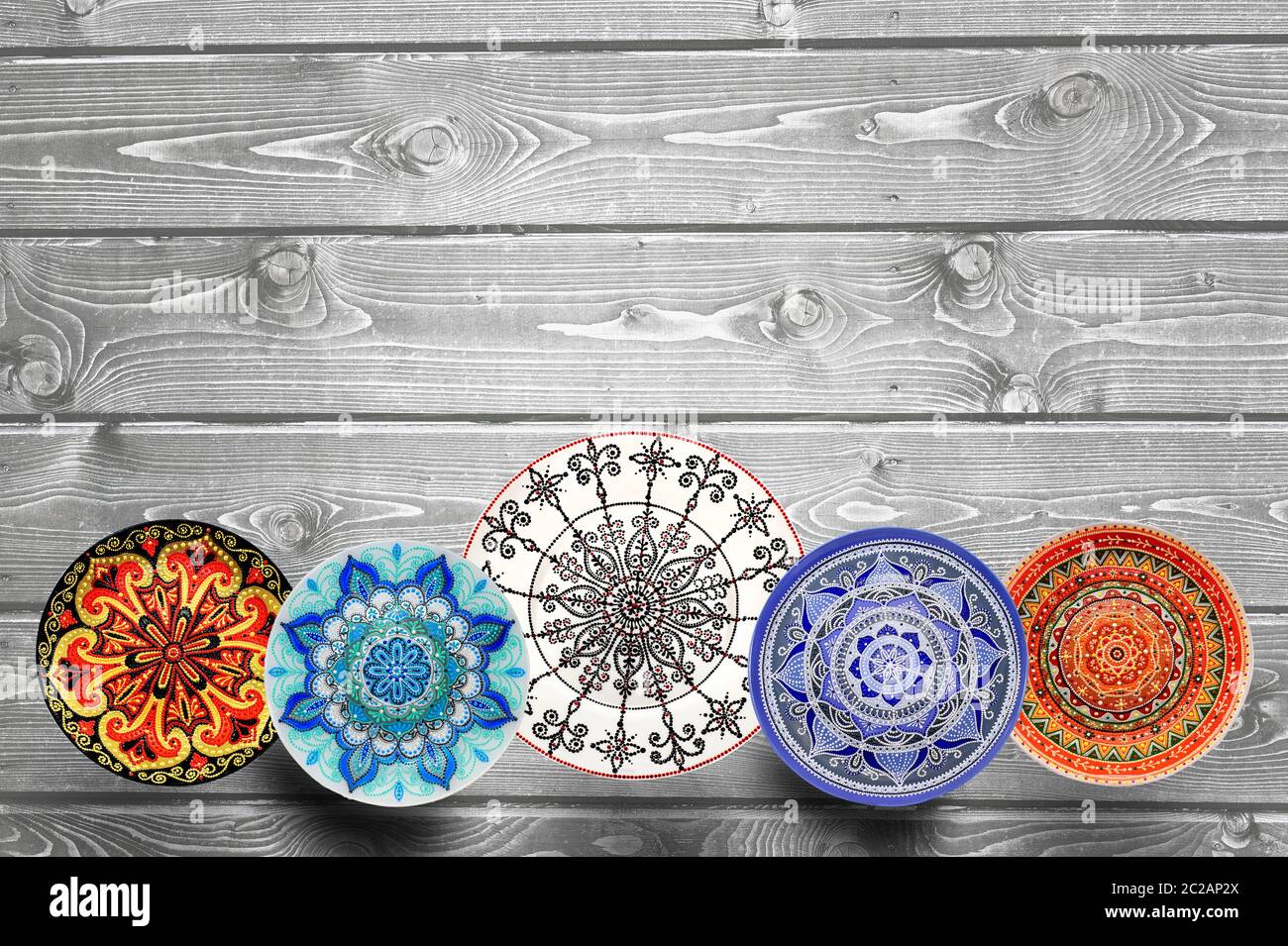 Impostare decorativo di piastre in ceramica dipinta a mano con colori acrilici su uno sfondo di legno con posto per il testo. Foto Stock