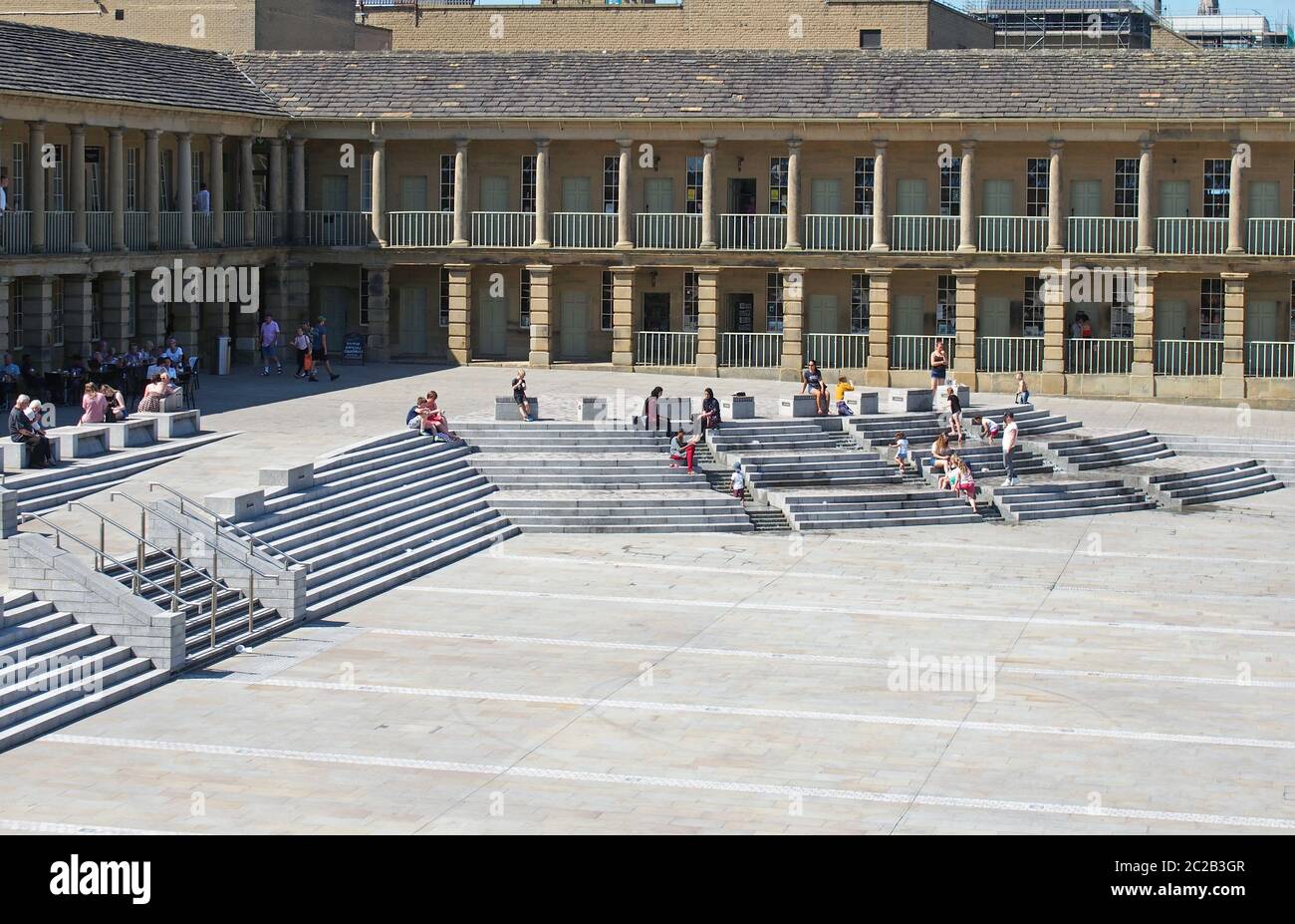 persone che si rilassano sui gradini e camminando attraverso la piazza della sala pezzi halifax nel west yorkshire Foto Stock